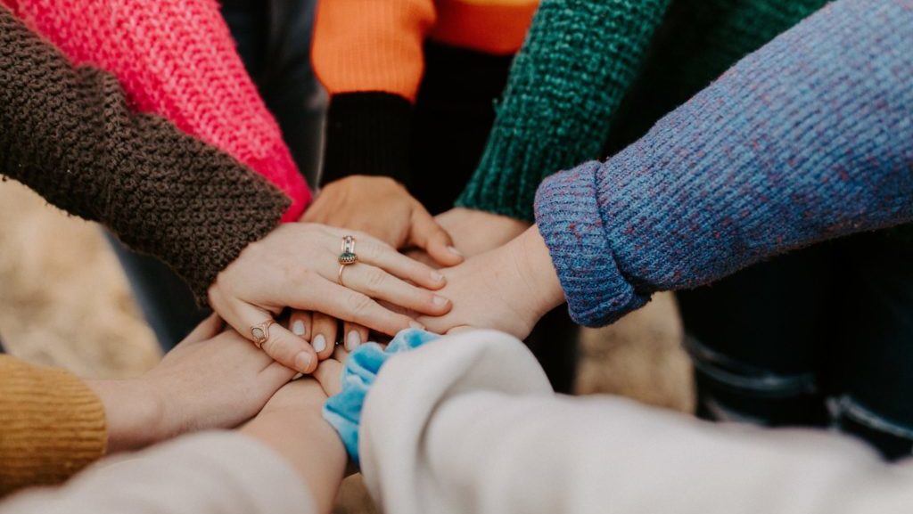 person in red sweater holding babys hand